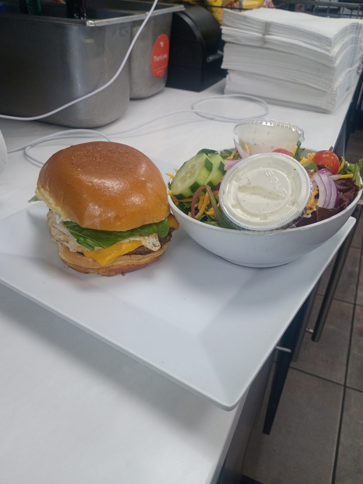 A cheeseburger with a fried egg and a side salad
