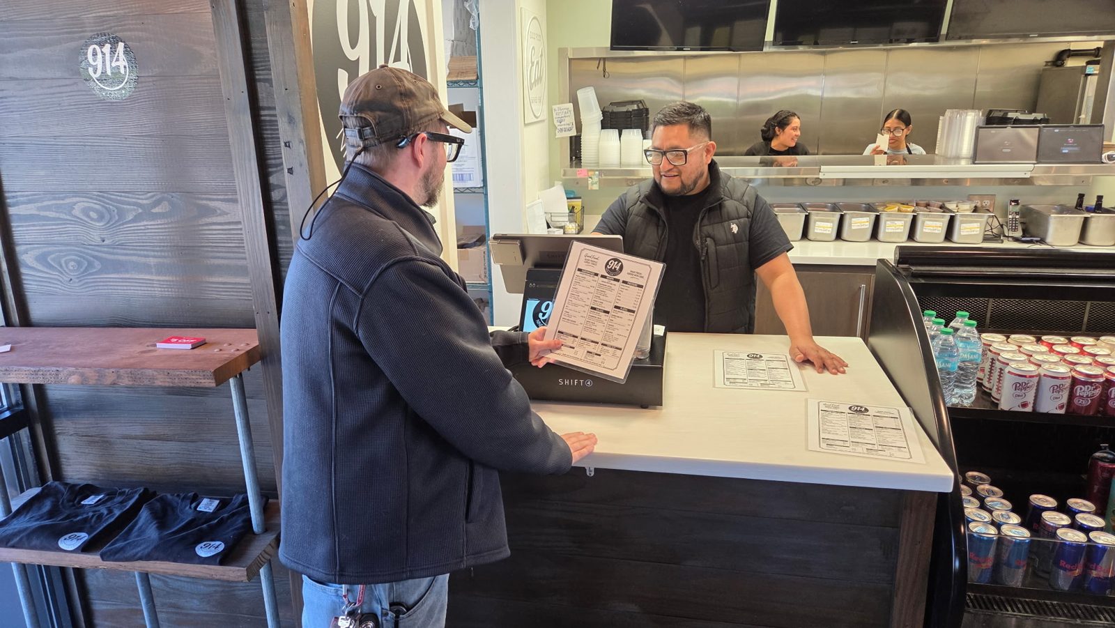 A customer ordering at the Nine One Four counter, the kitchen team behind