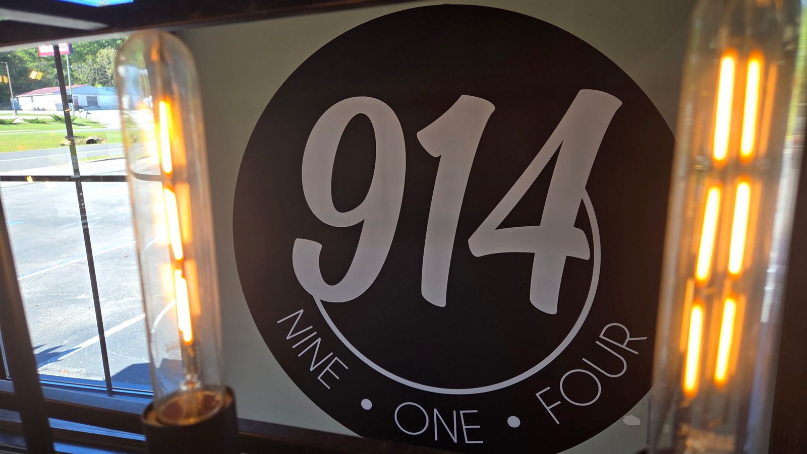 The 914 Nine One Four logo on the wall between two glowing bulbs