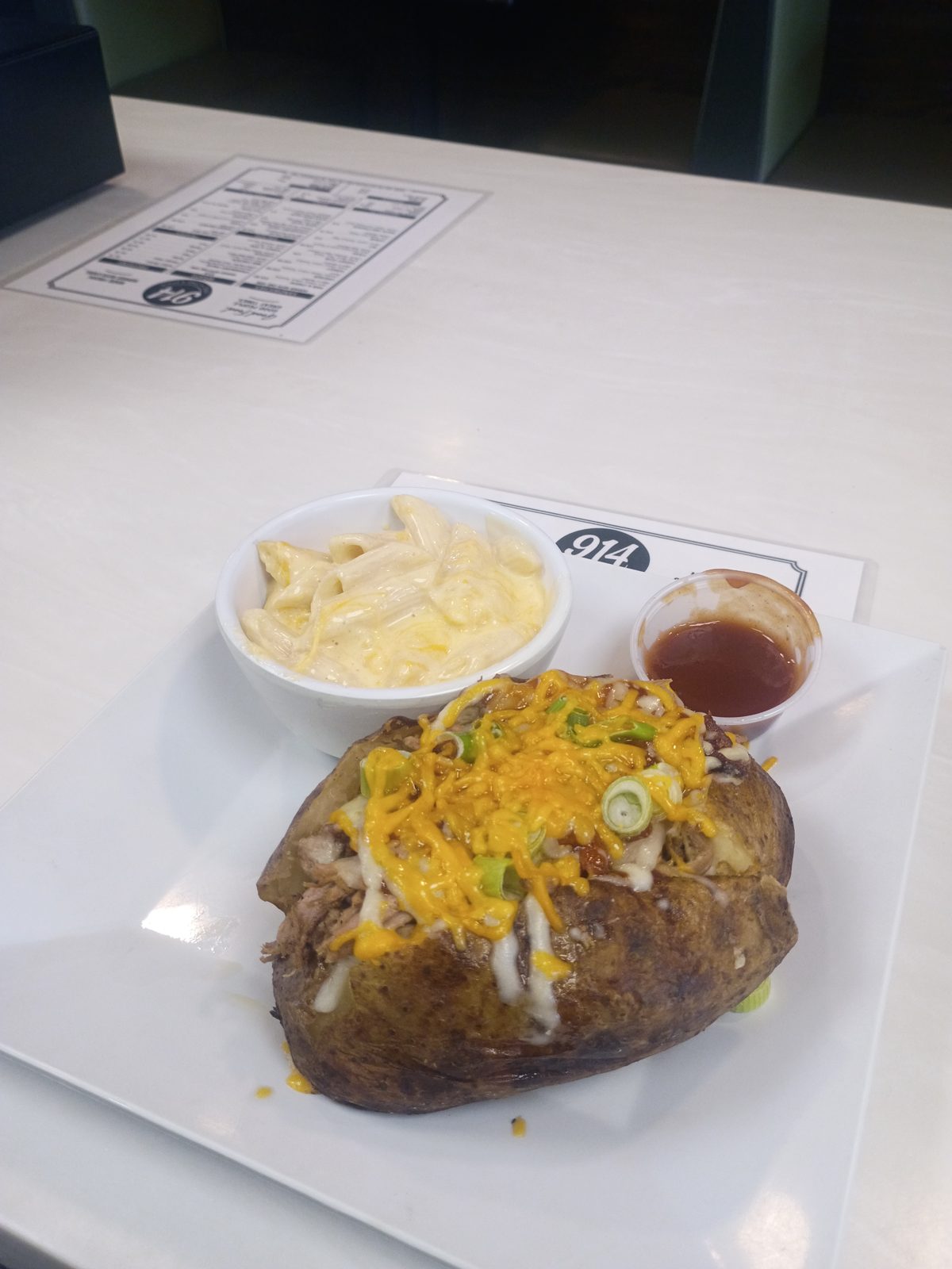 A loaded baked potato with mac and cheese on the side